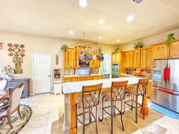 a dining hall with stainless steel appliances kitchen island granite countertop a dining table and chairs