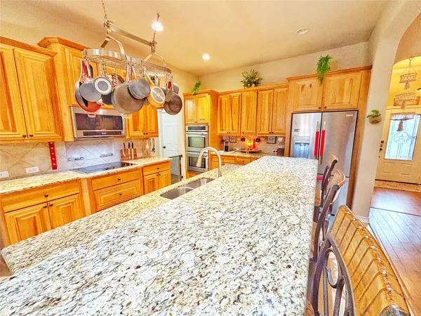 a large kitchen with stainless steel appliances kitchen island granite countertop a sink and cabinets