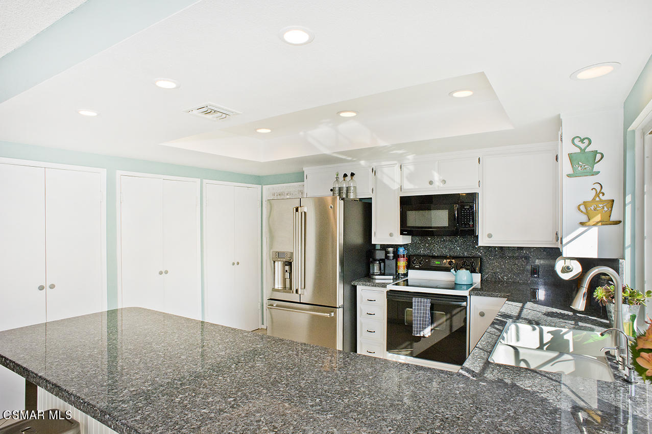 2386 Fitzgerald Road Simi Valley, CA 93065 - Photo 8 of 28 a kitchen with stainless steel appliances granite countertop a refrigerator oven stove a sink a dining table and chairs with wooden floor