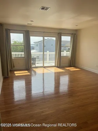 a view of an empty room with wooden floor and windows