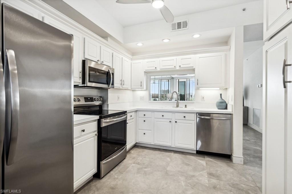 170 Lenell Road, Unit 403 Fort Myers Beach, FL 33931 - Photo 8 of 23 a kitchen with white cabinets and stainless steel appliances