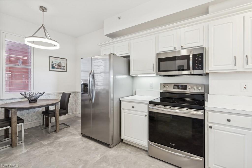 170 Lenell Road, Unit 403 Fort Myers Beach, FL 33931 - Photo 9 of 23 a kitchen with stainless steel appliances a stove a microwave and white cabinets
