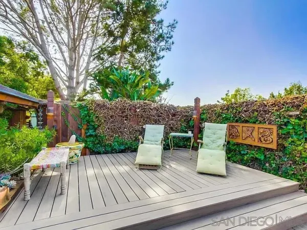 a view of a patio with table and chairs and potted plants with wooden floor and fence