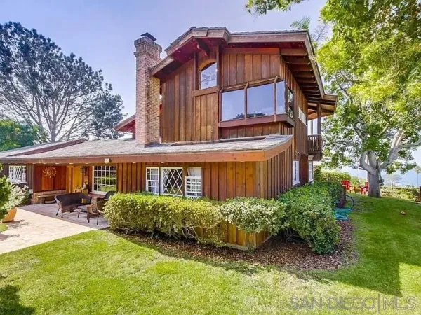 a view of a house with a big yard and large trees