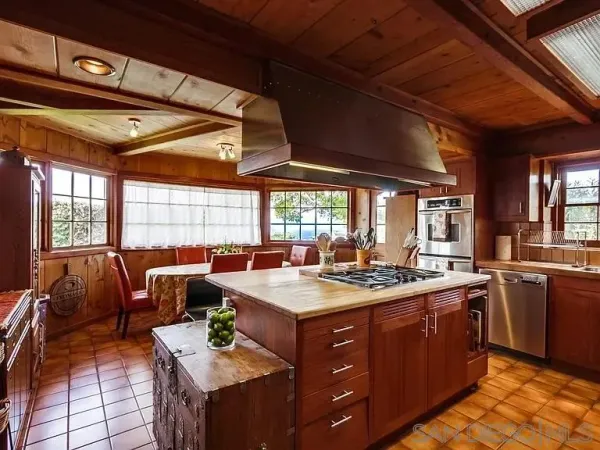 a kitchen with a stove a sink a refrigerator dining table and chairs