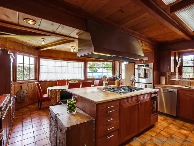 a kitchen with a stove a sink a refrigerator dining table and chairs