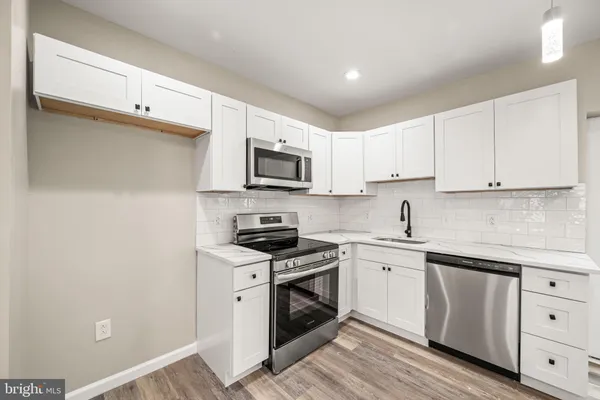 a kitchen with white cabinets stainless steel appliances and sink