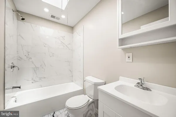 a bathroom with a bathtub shower sink vanity mirror and toilet