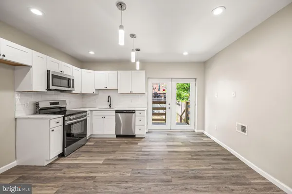 a large kitchen with kitchen island a sink a stove a oven a counter space and cabinets