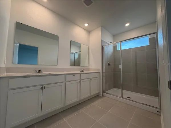 a spacious bathroom with a mirror a shower and a sink