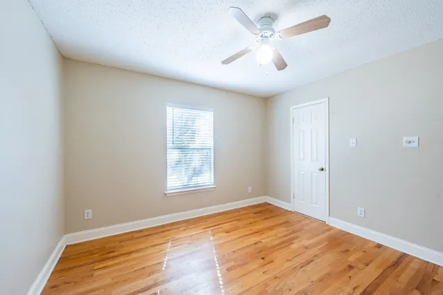 an empty room with wooden floor and ceiling fan