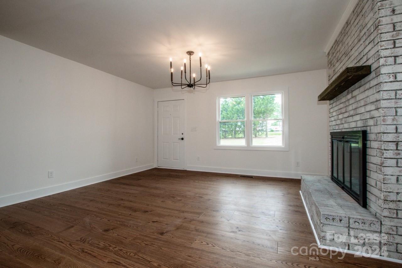 4892 Highway 16 Denver, NC 28037 - Photo 12 of 46 an empty room with wooden floor fireplace and windows