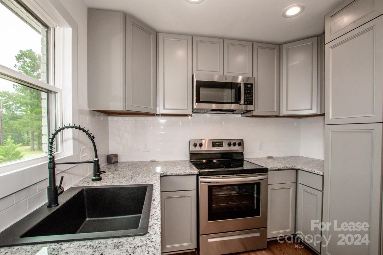 4892 Highway 16 Denver, NC 28037 - Photo 23 of 46 a kitchen with granite countertop a sink stove and microwave