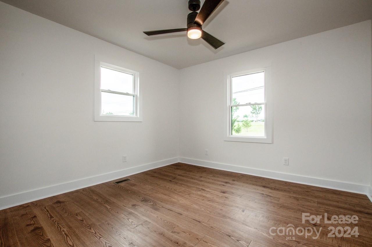 4892 Highway 16 Denver, NC 28037 - Photo 32 of 46 an empty room with wooden floor ceiling fan and windows