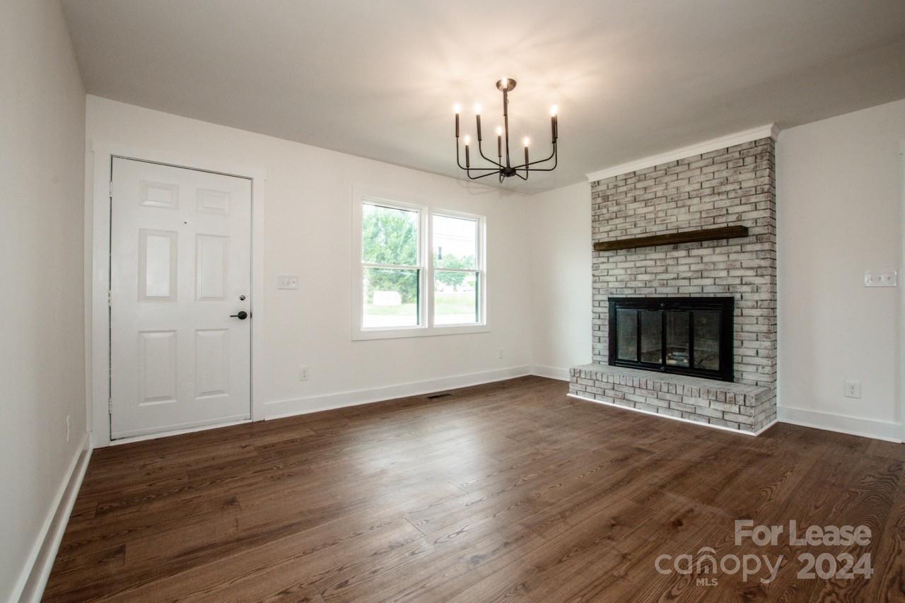 4892 Highway 16 Denver, NC 28037 - Photo 9 of 46 an empty room with wooden floor fireplace and window