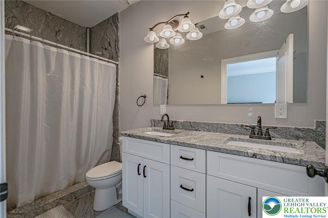 1490 East 7th Street Bethlehem, PA 18015 - Photo 14 of 22 a bathroom with a granite countertop sink a toilet and a mirror