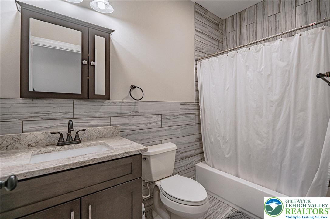 1490 East 7th Street Bethlehem, PA 18015 - Photo 19 of 22 a bathroom with a granite countertop sink toilet a mirror and shower