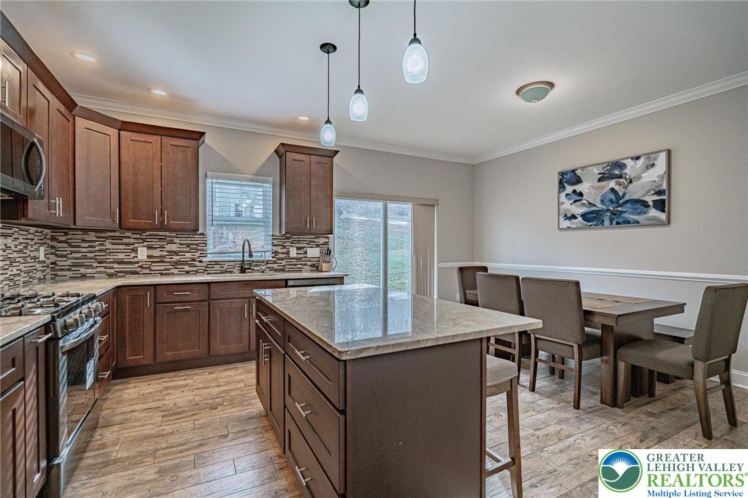 1490 East 7th Street Bethlehem, PA 18015 - Photo 9 of 22 a kitchen with a stove a sink a microwave a dining table and chairs