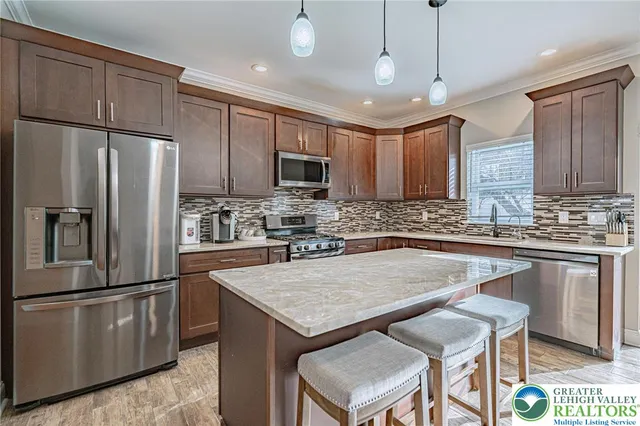 a kitchen with granite countertop a refrigerator a sink a stove a microwave and island