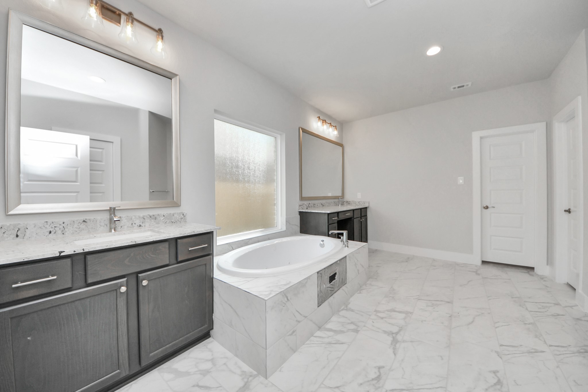 3110 Native Spg Drive Spring, TX 77373 - Photo 18 of 34 Escape to a spa-like oasis in this primary bathroom. Enjoy a walk-in shower with tile surround, a separate garden tub with custom detailing, and an elegant vanity featuring light countertops, modern hardware, and beautiful vanity lights. Experience luxury and relaxation in every detail. Sample photo of completed home with similar floor plan. Actual colors and selections may vary.