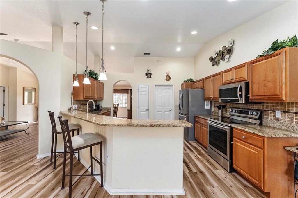 9910 Southeast 138th Loop Summerfield, FL 34491 - Photo 16 of 69 a kitchen with stainless steel appliances kitchen island granite countertop a stove a sink a refrigerator and chairs