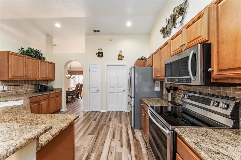 9910 Southeast 138th Loop Summerfield, FL 34491 - Photo 17 of 69 a kitchen with stainless steel appliances granite countertop a stove top oven a sink dishwasher a refrigerator and a oven with wooden floor