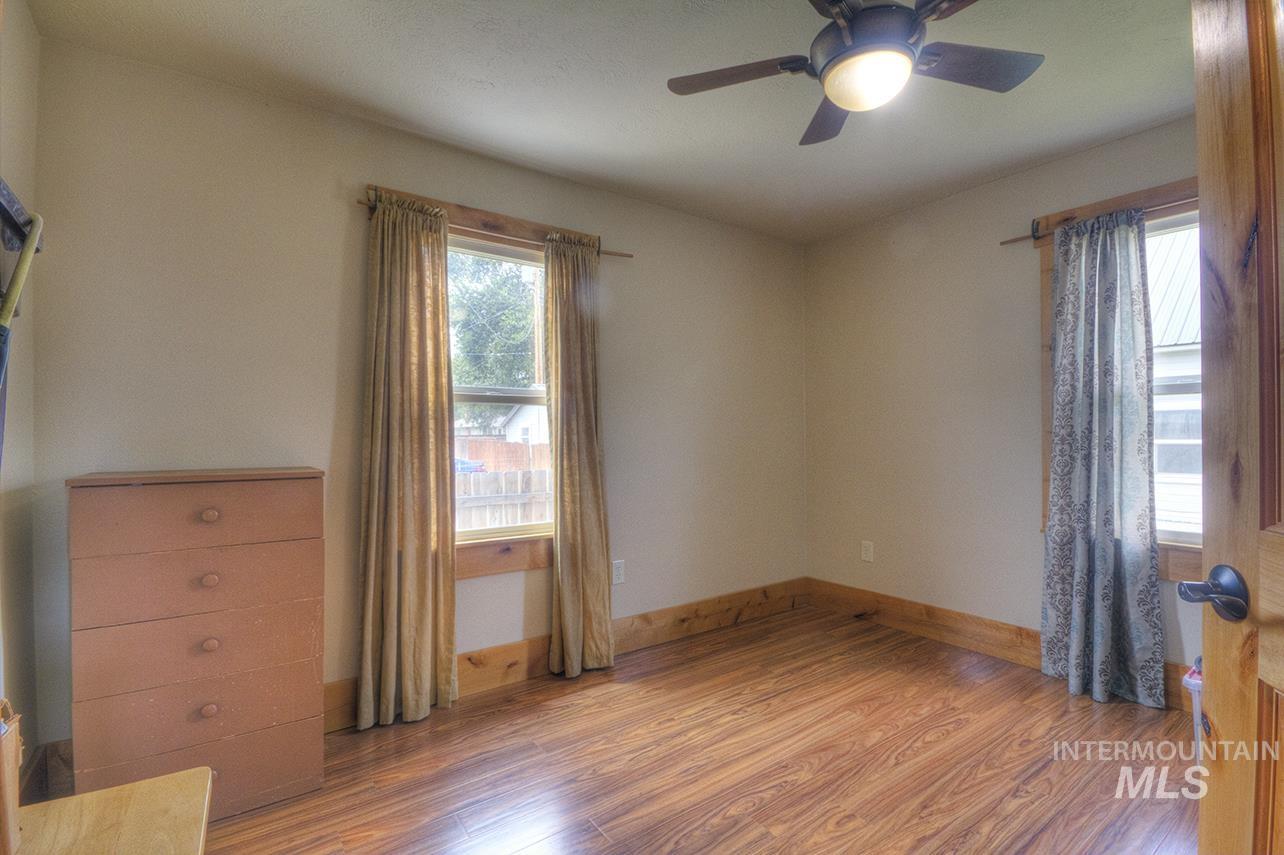 351 West Main Street South Vale, OR 97918 - Photo 20 of 33 Room with wood-finish flooring, two windows, wood trim, and a ceiling fan with integrated lighting