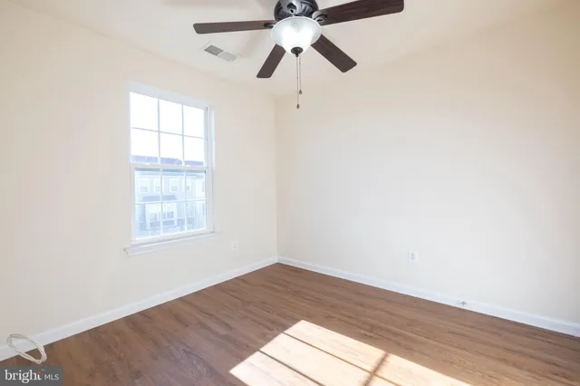 an empty room with wooden floor fan and windows