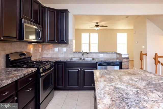 a kitchen with stainless steel appliances granite countertop a refrigerator a sink dishwasher a oven and a dining table with the view of kitchen