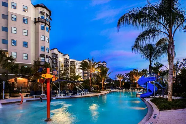 a view of a swimming pool with a lawn chairs and palm trees