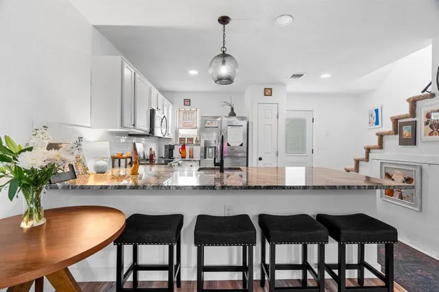 a kitchen with granite countertop a table chairs stove and cabinets