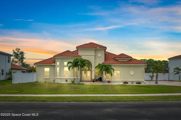 a front view of a house with a garden and trees