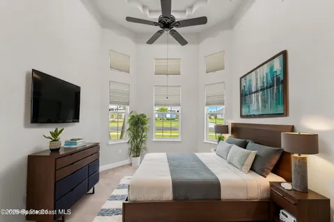 a bedroom with a bed a flat screen tv and a chandelier