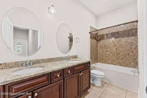 a bathroom with a granite countertop bathtub sink mirror vanity and toilet