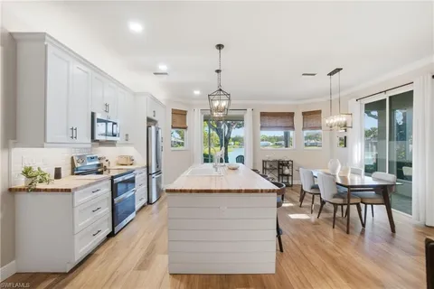 a kitchen with stainless steel appliances kitchen island granite countertop a stove a refrigerator a kitchen island a dining table and chairs with wooden floor