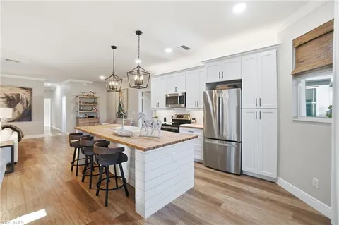 a kitchen with stainless steel appliances a dining table chairs stove and refrigerator
