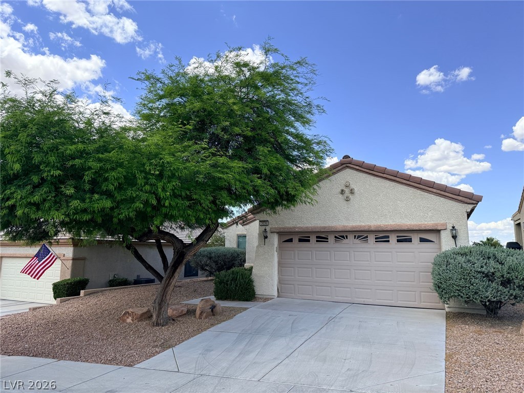 3036 Fort Stanwix Road Henderson, NV 89052 - Photo 1 of 18 A spacious concrete driveway leads to an attached garage set against a desert landscape.