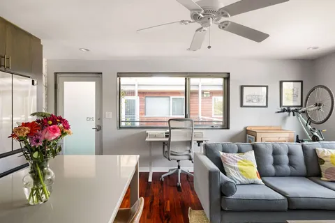a living room with furniture a large window and wooden floor