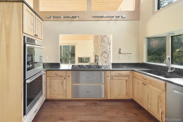 a kitchen with a refrigerator wooden floor a sink and a window