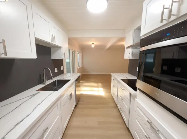 a large kitchen with stainless steel appliances wooden cabinets and a stove top oven