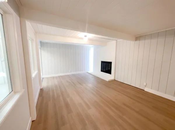a view of empty room with wooden floor and fireplace