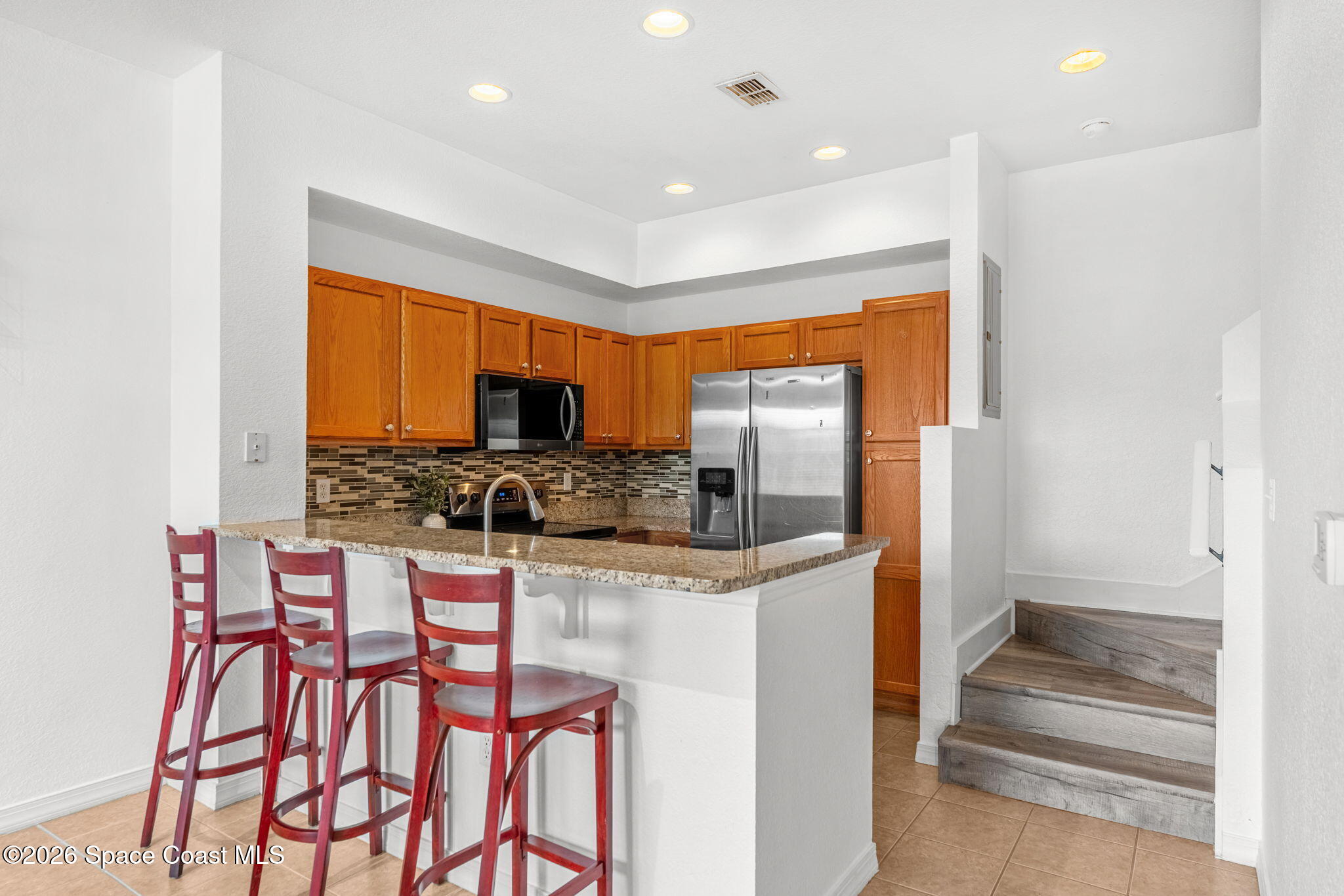 110 Turpial Way, Unit 106 Melbourne, FL 32901 - Photo 16 of 50 a kitchen with stainless steel appliances kitchen island granite countertop a refrigerator and microwave