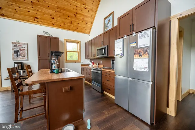a kitchen with kitchen island a counter top space a sink stainless steel appliances and cabinets