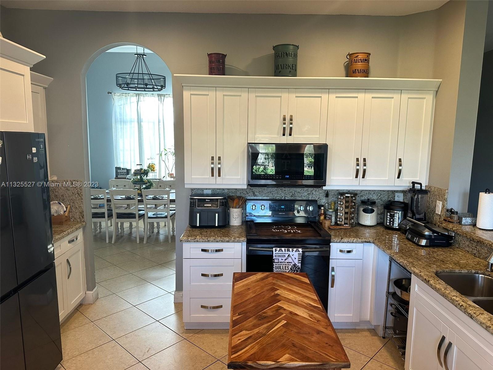 20565 Southwest 326th Street Homestead, FL 33030 - Photo 9 of 28 a kitchen with stainless steel appliances kitchen island granite countertop a stove a sink and a microwave