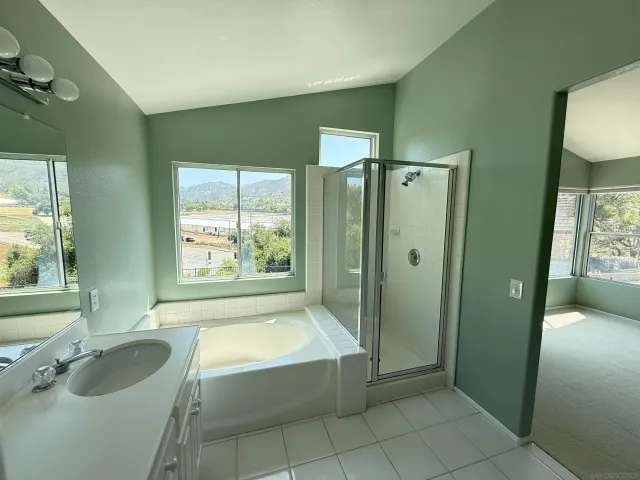a bathroom with a granite countertop tub sink a mirror and shower
