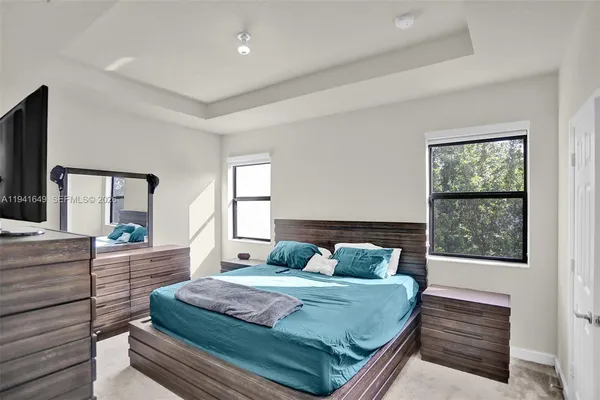 a bedroom with a large bed and a flat tv screen on dresser