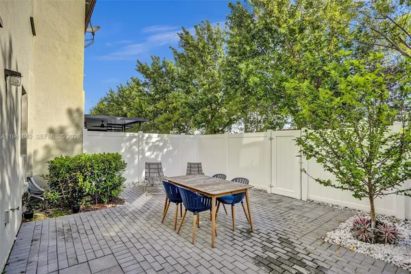 a patio with table and chairs and potted plants