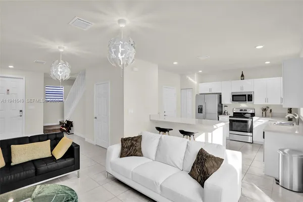 a living room with furniture kitchen and a chandelier