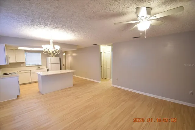 a large kitchen with kitchen island a stove a sink dishwasher a refrigerator and a dining table with wooden floor