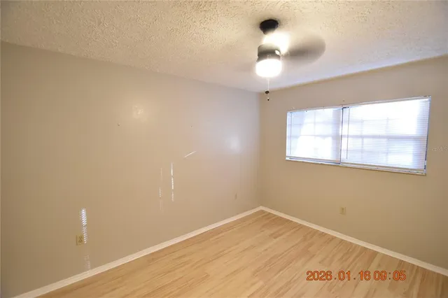 an empty room with a window and chandelier fan